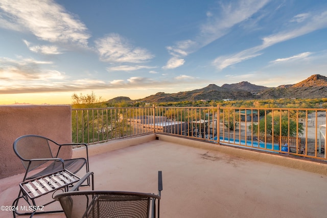 patio terrace at dusk featuring a mountain view and a swimming pool