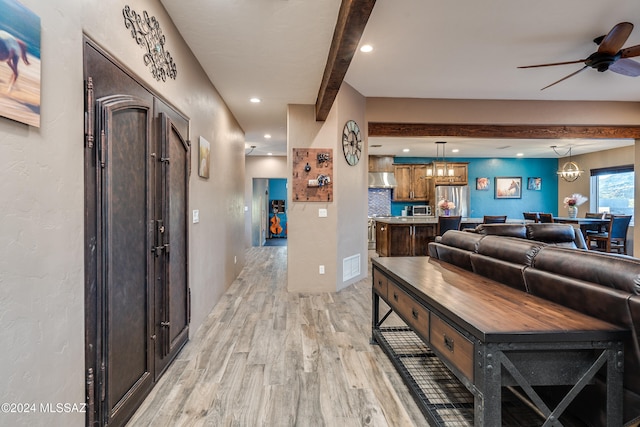 living room featuring beamed ceiling, ceiling fan with notable chandelier, and light hardwood / wood-style floors