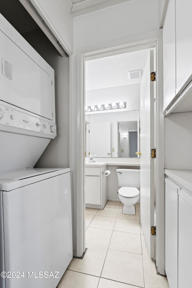 clothes washing area featuring light tile patterned floors and stacked washer / drying machine