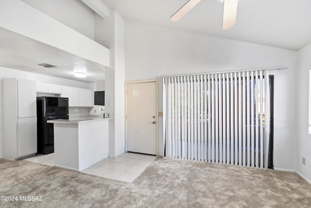 kitchen featuring white cabinets, black fridge, and light carpet