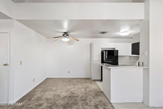 kitchen with white cabinetry, ceiling fan, kitchen peninsula, light colored carpet, and black refrigerator