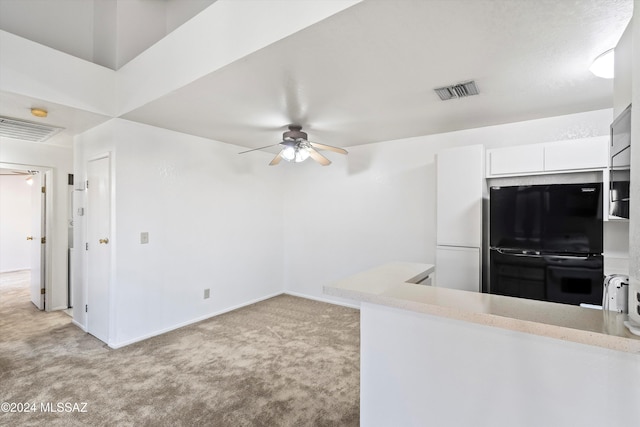 kitchen with light carpet, white cabinets, black appliances, and ceiling fan