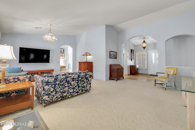 living room with lofted ceiling, carpet floors, and a chandelier