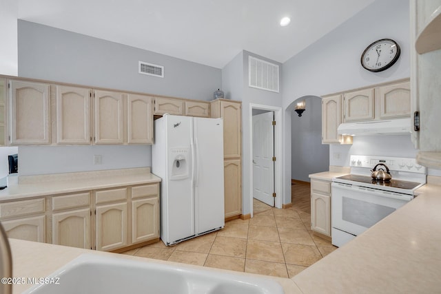 kitchen with lofted ceiling, light tile patterned floors, and white appliances