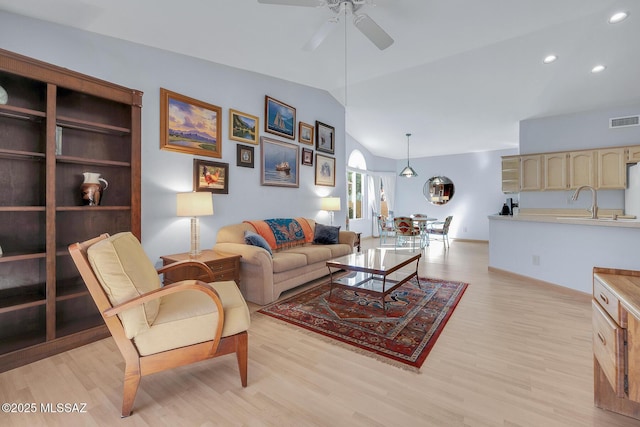 living room with ceiling fan, lofted ceiling, and light hardwood / wood-style flooring