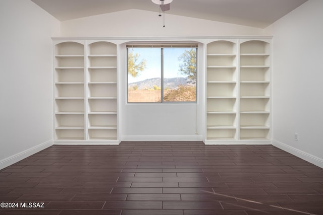 empty room featuring lofted ceiling, built in features, ceiling fan, and dark hardwood / wood-style floors