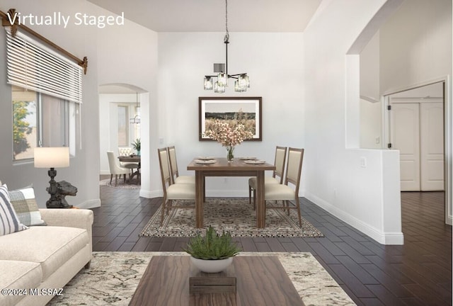 dining room with dark hardwood / wood-style flooring, a chandelier, and a high ceiling