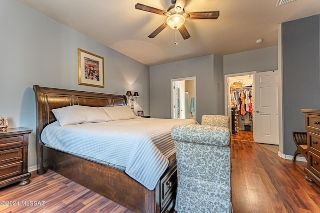 bedroom featuring connected bathroom, a spacious closet, ceiling fan, dark wood-type flooring, and a closet