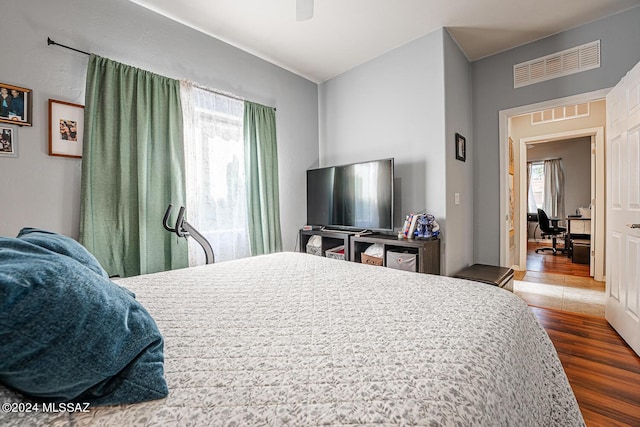 bedroom with hardwood / wood-style flooring, ceiling fan, and multiple windows