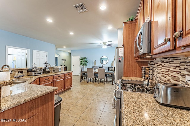 kitchen with light stone countertops, sink, ceiling fan, stainless steel appliances, and light tile patterned flooring