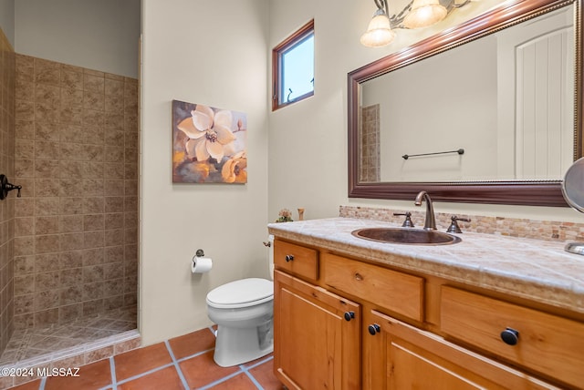 bathroom featuring tile patterned flooring, a tile shower, vanity, and toilet