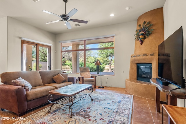 living room featuring tile patterned floors, ceiling fan, and a large fireplace