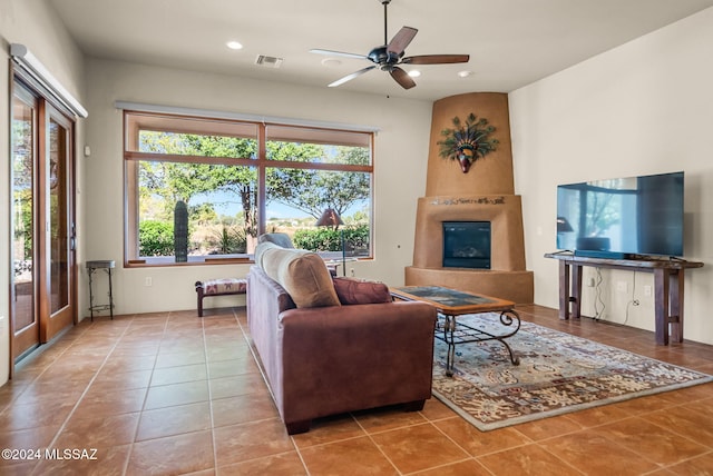 tiled living room with ceiling fan and a fireplace