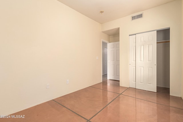 unfurnished bedroom featuring concrete floors and a closet