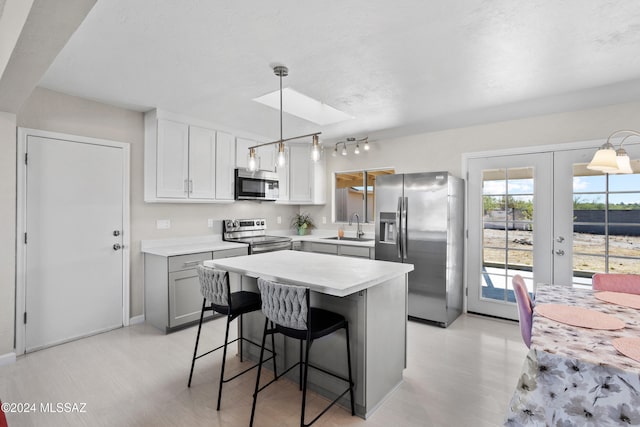 kitchen with appliances with stainless steel finishes, french doors, sink, a kitchen island, and hanging light fixtures