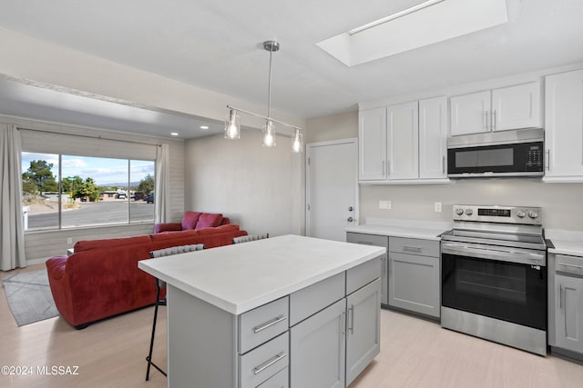 kitchen with light wood-type flooring, gray cabinetry, a breakfast bar, stainless steel appliances, and hanging light fixtures