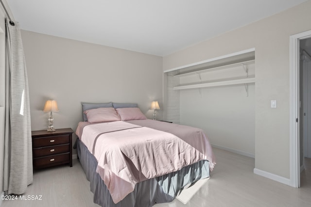 bedroom with a closet, beamed ceiling, and light hardwood / wood-style floors