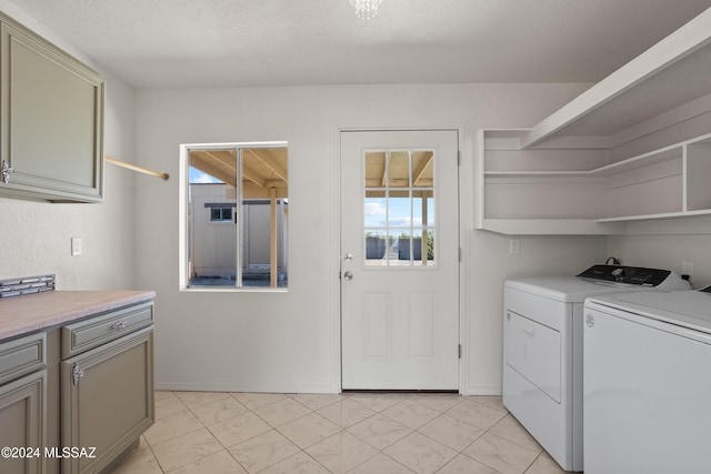 clothes washing area with washing machine and dryer, plenty of natural light, cabinets, and a textured ceiling