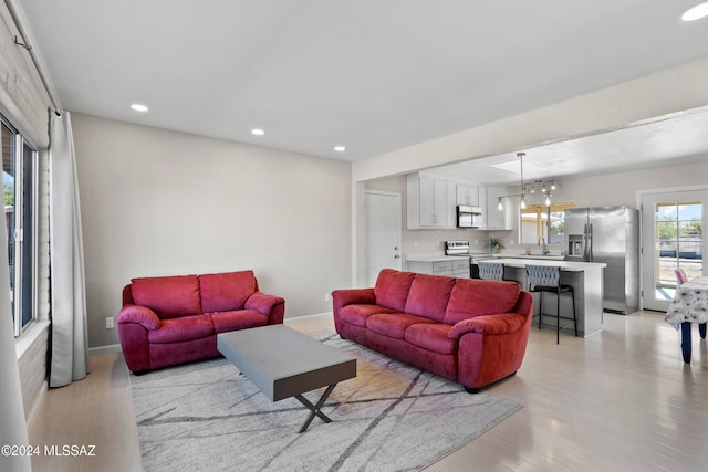 living room featuring a chandelier, sink, and light hardwood / wood-style flooring