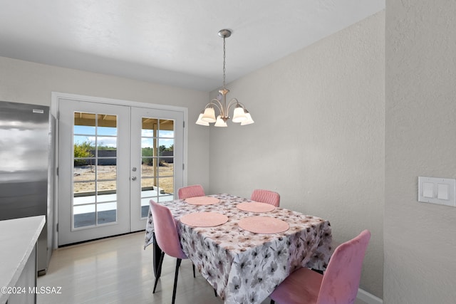 dining area featuring french doors, light wood-type flooring, and a notable chandelier