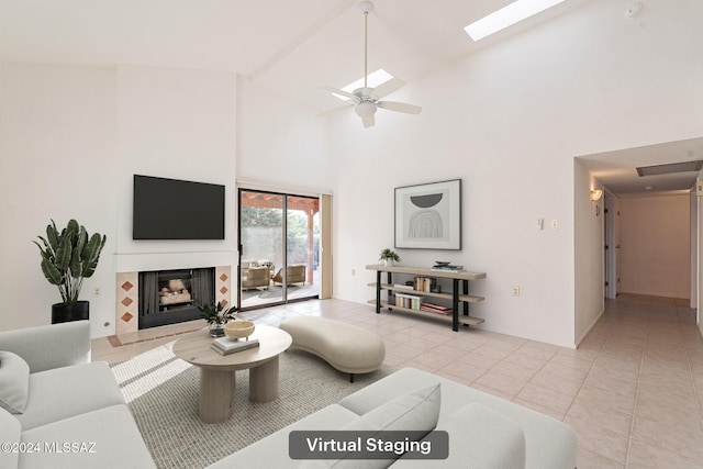 living room with ceiling fan, light tile patterned floors, high vaulted ceiling, and a skylight