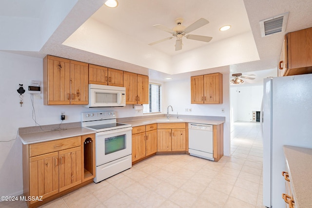 kitchen featuring ceiling fan, white appliances, sink, and a tray ceiling