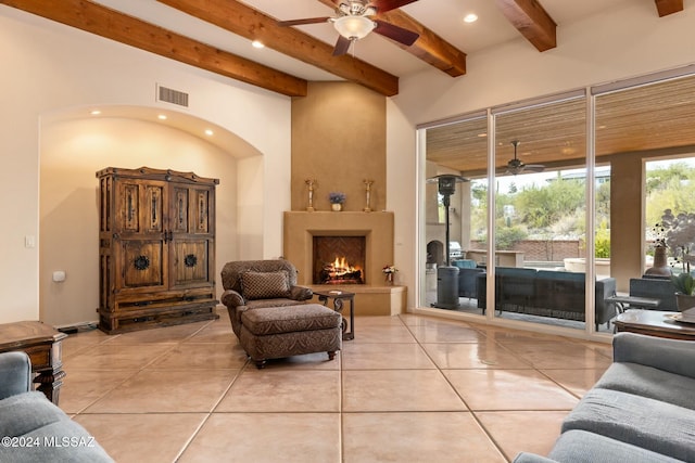 living room featuring beamed ceiling, ceiling fan, and light tile patterned floors