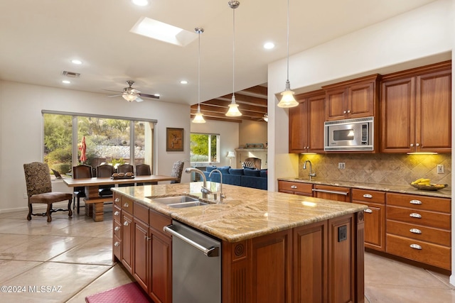 kitchen featuring appliances with stainless steel finishes, a skylight, sink, hanging light fixtures, and an island with sink