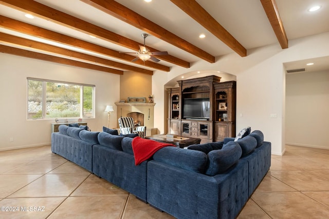 living room featuring beamed ceiling, a large fireplace, ceiling fan, and light tile patterned flooring