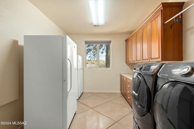 laundry area with washer and clothes dryer, light tile patterned flooring, and cabinets