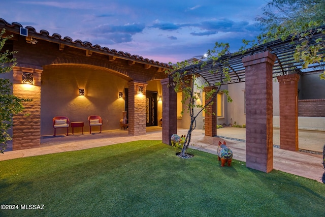 patio terrace at dusk featuring a pergola and a yard