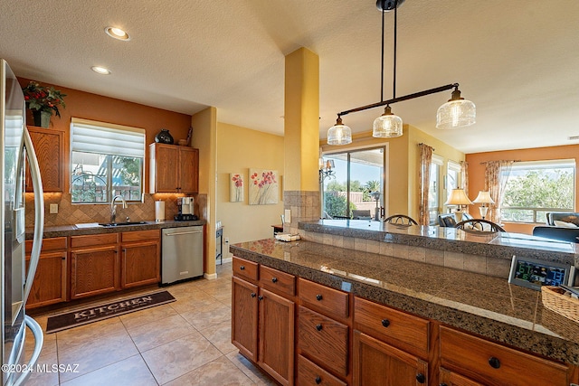 kitchen featuring sink, pendant lighting, decorative backsplash, light tile patterned flooring, and appliances with stainless steel finishes