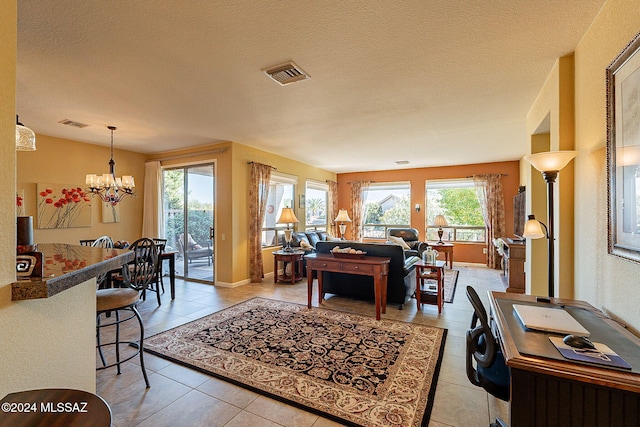 living room with a notable chandelier, light tile patterned flooring, plenty of natural light, and a textured ceiling