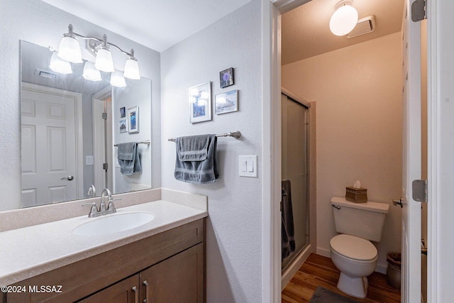 bathroom featuring hardwood / wood-style floors, vanity, an enclosed shower, and toilet