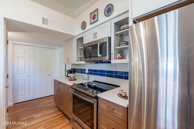 kitchen featuring tasteful backsplash, white cabinetry, stainless steel appliances, and light hardwood / wood-style flooring