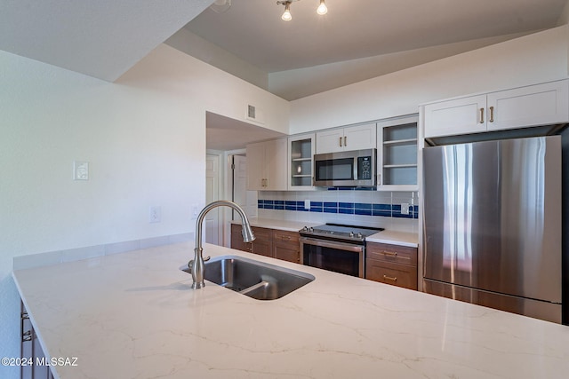 kitchen featuring white cabinets, sink, appliances with stainless steel finishes, tasteful backsplash, and light stone counters