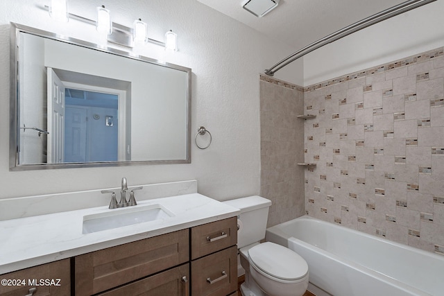 full bathroom with a textured ceiling, vanity, toilet, and tiled shower / bath