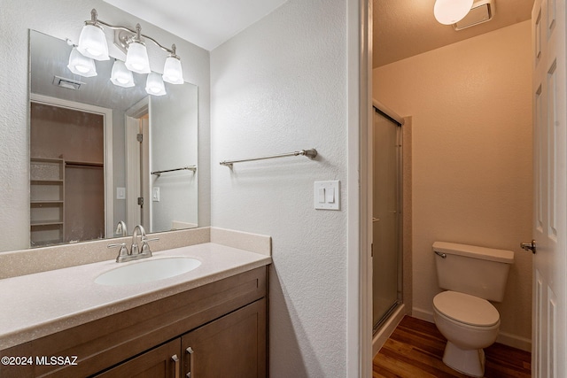 bathroom featuring toilet, vanity, a shower with shower door, and hardwood / wood-style flooring