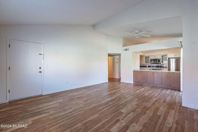 unfurnished living room featuring ceiling fan, sink, lofted ceiling, and light wood-type flooring