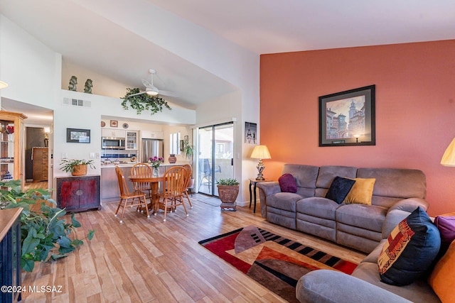 living room with light hardwood / wood-style floors, high vaulted ceiling, and ceiling fan