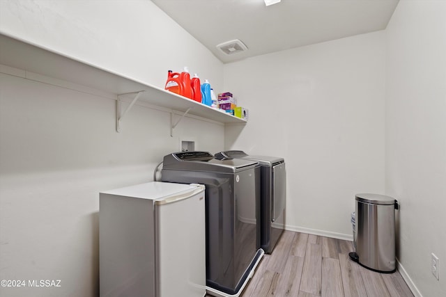 laundry area featuring washing machine and dryer and light hardwood / wood-style flooring