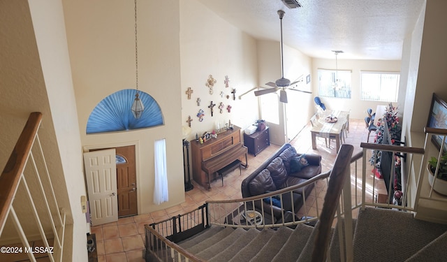 tiled foyer entrance featuring ceiling fan with notable chandelier and a textured ceiling