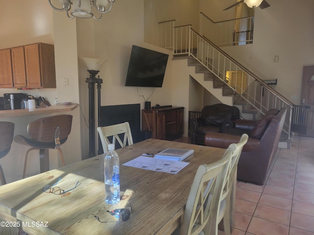 tiled dining area with a high ceiling and a notable chandelier