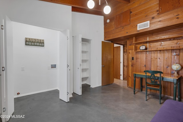 interior space with a high ceiling and wooden walls