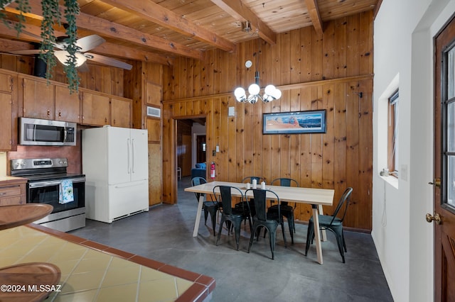 dining area with ceiling fan with notable chandelier, wood ceiling, a towering ceiling, beamed ceiling, and wood walls