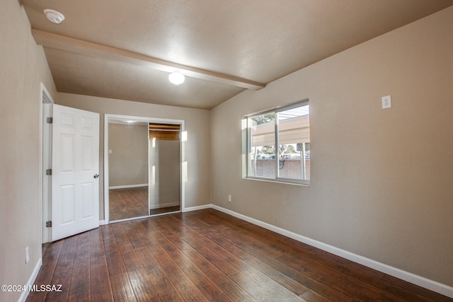 unfurnished bedroom with beam ceiling, dark hardwood / wood-style flooring, and a closet