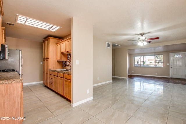 kitchen featuring ceiling fan, sink, tasteful backsplash, stainless steel fridge, and light tile patterned floors