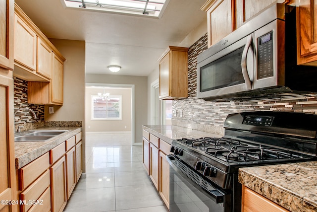 kitchen featuring decorative backsplash, black range with gas cooktop, sink, light tile patterned floors, and a chandelier