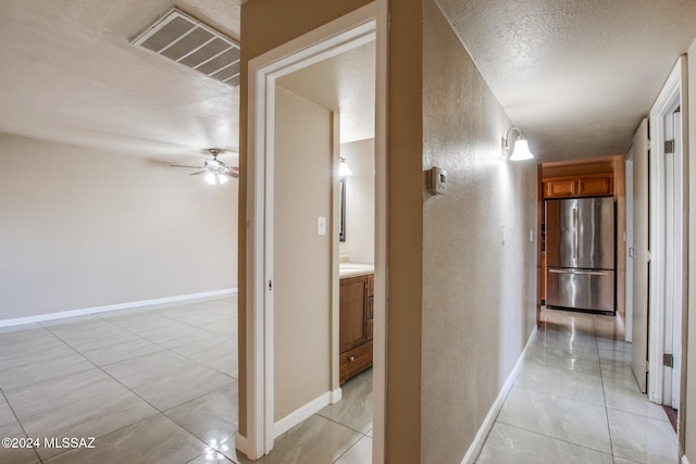 corridor with light tile patterned floors and a textured ceiling