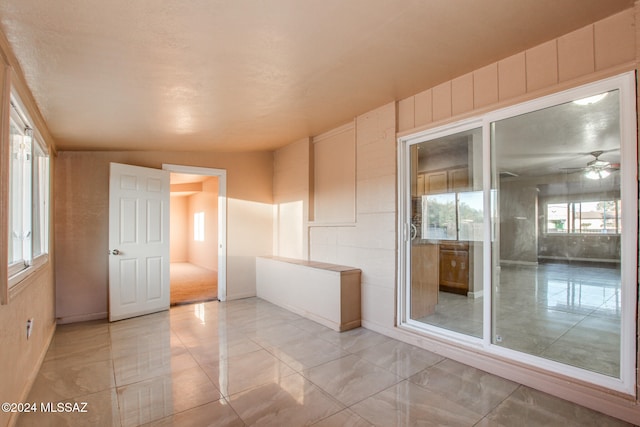 unfurnished room featuring ceiling fan, plenty of natural light, and lofted ceiling